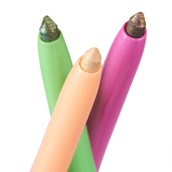 Trio of Chrome on Chrome ColourPop Chrome Crème Gel Liner pencils crossing to showcase multichrome tips - champagne gold, emerald teal, and smoky plum - housed in pastel peach, green, and magenta barrels on a white background.