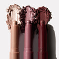 Three Rose Goals ColourPop Shadow Stix showcase creamy swatches - champagne shimmer, rosy mauve metallic, and deep burgundy - smeared behind the twist-up pencils on a white backdrop, highlighting the eyeshadow stick trio.