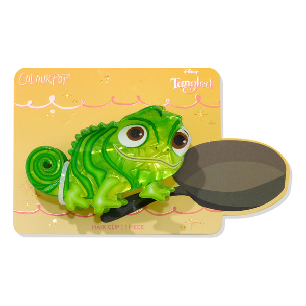 Tangled Pascal Hair Clip securing hair, shaped like a glossy translucent green chameleon with big brown eyes, displayed on a yellow Disney Tangled backing card with ColourPop branding; Tools and Accessories, 1 piece.