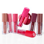 ColourPop Lip Stain Pop Stars tubes standing, leaning, and one lying to show nude, pink, and berry shades, paired with a hot‑pink Hydra Pop PopSocket phone grip, arranged on a glossy white studio surface.