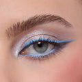 Shimmery silver eyeshadow with graphic pastel blue liner on a close-up eye, showcasing Rainbow Rush ColourPop Shadow Palette Set for a bold, icy look, with defined lashes, a groomed brow, and a soft pink cheek.
