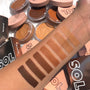 Arm swatches display a gradient of creamy bronzer shades from deep to light, highlighting the Light shade of ColourPop SOL Face & Body Bronzing Balm, surrounded by open peach-lidded SOL Body compacts on a tabletop.