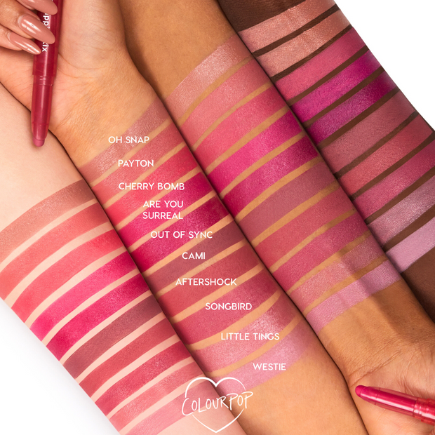 After Shock ColourPop Lippie Stix swatch showing a rosy mauve stripe across four forearms of different skin tones, compared alongside labeled shades like Cami and Songbird, with a twist-up lip crayon visible for product reference.
