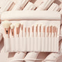 Ultimate Brush Roll displaying a full set of soft white-bristle makeup brushes with rose-gold ferrules neatly slotted in a blush pink travel roll, set on matching rolled cases - ColourPop Makeup Brush Kit for face and eye application.