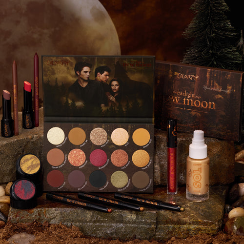 Twilight New Moon x ColourPop Full Collection set displayed on rustic stone, featuring a New Moon eyeshadow palette with warm shimmer shades, lip crayons, gel liners, loose pigments, lip gloss, and SOL body product in a moody forest moonlit backdrop, perfect for Twilight ColourPop makeup fans.
