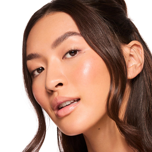 Glossy lips catch the light as a model wears Pretty in Pastels, the ColourPop Glossy Lip Balm Trio, delivering a sheer peachy-pink tint and hydrated shine; close-up beauty shot on a white background highlighting dewy, natural makeup.