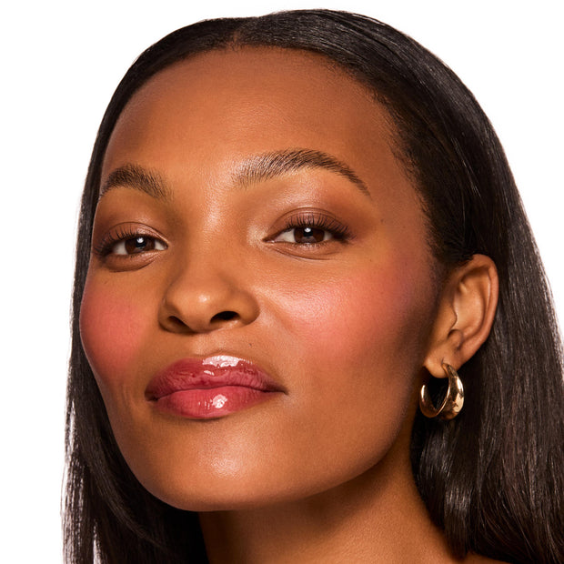 Glossy berry lips demonstrate the ColourPop Gloss Goals Full Collection Set on a close-up model, with dewy blush, soft neutral eyes, and a gold hoop earring against a clean white studio background.