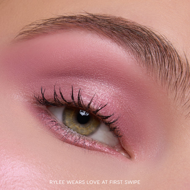 Close-up of a hazel eye wearing Heart to Get Love At First Swipe Shadow Stix, showing shimmery rose-pink eyeshadow blended from lash line to brow for a soft, romantic makeup look on smooth skin.