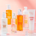 BFD Oil Cleanser face cleanser by Fourth Ray Beauty standing with a white pump and pale golden oil, displayed among companion cleansers on clear acrylic risers against a soft pink gradient; ColourPop skincare product shot.