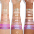 Three forearms with different skin tones display swatches of Colourpop Hallucinogenius Jelly Much Shadow eyeshadow shades, from champagne neutrals to vivid iridescent pinks and purples, showing shimmer payoff and color range.