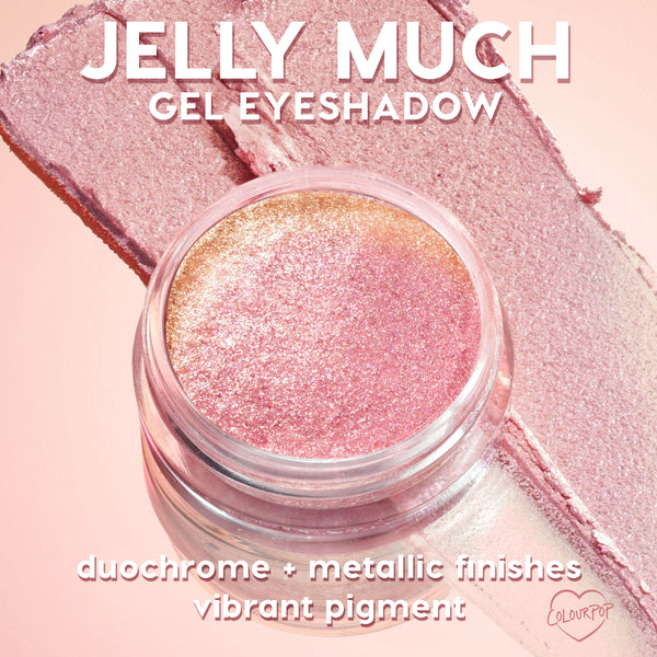 Open jar of ColourPop Jelly Much Shadow, Buzzy, gleams with duochrome pink-to-gold metallic shimmer, resting on matching swatches over a blush-pink backdrop; gel eyeshadow formula shows vibrant pigment and reflective, long-wear sparkle.