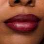 Lips wear ColourPop Lux Lipstick in Slow Burn, showing a rich burgundy-berry satin finish with soft, blurred edges; macro close-up highlights creamy texture, full coverage, and smooth application.