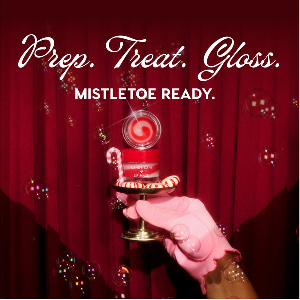 ColourPop Candy Cane Lip Mask jar with red‑white swirled balm opened, held on a small pedestal by a pink‑gloved hand beside a candy cane and peppermint, bubbles drifting before deep red curtains with the holiday headline Prep. Treat. Gloss. Mistletoe Ready.