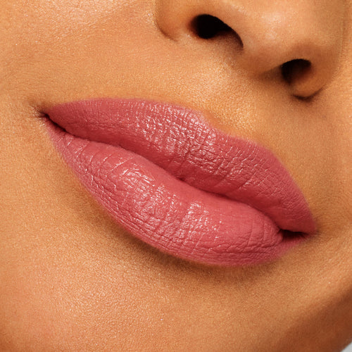 Full lips wearing ColourPop Lippie Stix “It’s Giving,” a rosy mauve pink with a creamy satin sheen, showcasing smooth, even coverage in a close-up swatch against skin for true-to-color shade reference.