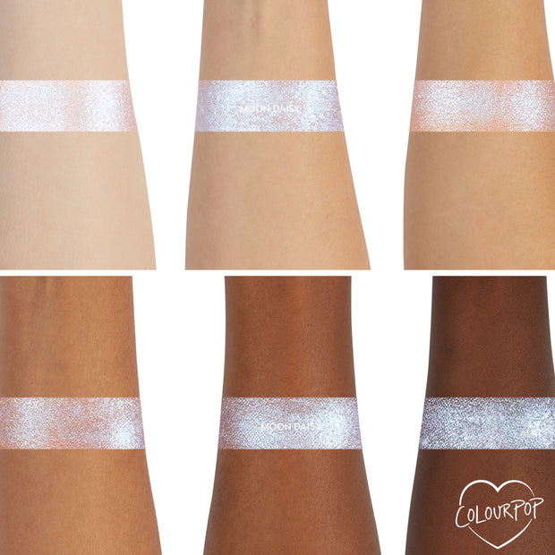 ColourPop Moon Daisy Super Shock Shadow swatches showing a high-shine icy lavender-blue shift across six arms from light to deep skin tones, demonstrating smooth metallic payoff and sparkle; ColourPop heart logo in the bottom right.