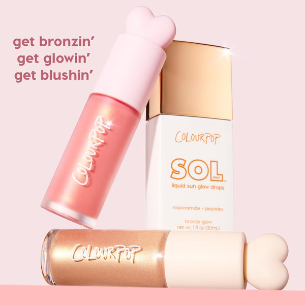 City Walk liquid blush by ColourPop, a rosy pink formula in a frosted bottle with a heart-shaped cap, tilts beside SOL Body liquid sun glow drops and a gold shimmer tube on a pastel pink background, promoting bronzing, glowing, and blushing.