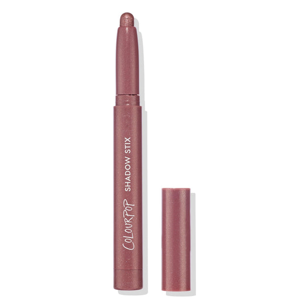ColourPop Shadow Stix in Next Spot stands uncapped with the rounded shimmer tip exposed, showing a rosy mauve metallic shade; slim pencil with ColourPop Shadow Stix branding, cap beside it on a clean white background.