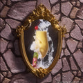 Ogress ColourPop Ultra Glossy Lip stands at the base of an ornate gold mirror, the pink lip gloss with green cap and ogre icon beside a smoky golden drink topped with a cherry, set against a medieval stone wall backdrop.