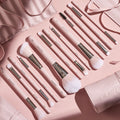Smoke 'N Roses Brush Roll displaying a full ColourPop Makeup Brush Kit: pink-handled powder, blush, eyeshadow, angled liner, and spoolie brushes with silver ferrules, arranged in a flat lay beside a blush-pink roll-up case embossed ColourPop.