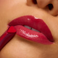 Heart-shaped red lip stick applicator sweeping shiny berry color onto smooth, parted lips in a tight studio macro, showcasing high-gloss finish from the A Shadow of Secrets Collection ColourPop Full Collection Set.