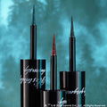 Three Colourpop Twilight Coven Graphix Ink Liner wands stand upright, showing fine macro tips coated in teal, red, and black glitter against a blurred teal forest background, highlighting the precise, dramatic liquid eyeliner colors.