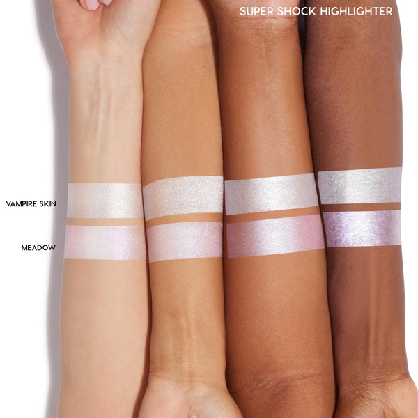 Vampire Skin swatched - an icy silver, high-shine ColourPop Super Shock Highlighter - striped across four forearms from light to deep skin tones, shown above a second Meadow swatch for comparison.