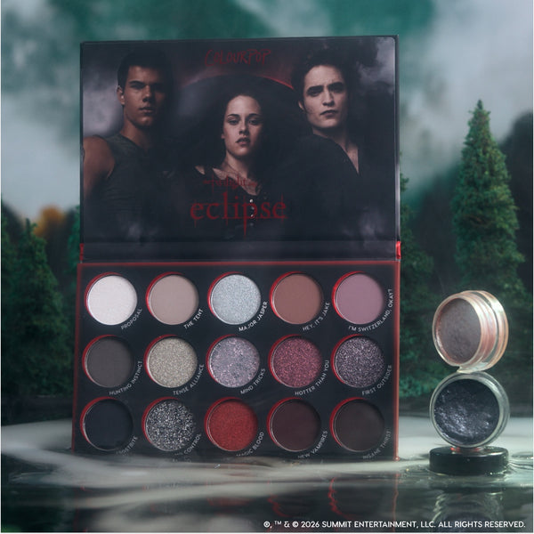 Eternal Eclipse eye trio from the Twilight x ColourPop collection standing open in a misty forest scene, showing 16 smokey shimmer and matte shadows plus a matching loose pigment pot in moody silver and charcoal tones.