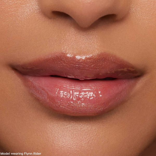 Glossy nude-pink lips wearing ColourPop Ultra Glossy Lip in Flynn Rider, reflecting a high-shine finish with subtle shimmer in a tight face close-up, showcasing smooth, hydrated texture for everyday wear.