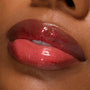 Glossy lips wearing Pack Member Lip Set, a sheer cherry-red tint with fine red shimmer and mirror shine on medium‑deep skin; close-up swatch highlights smooth, plump finish and sparkle for product detail; ColourPop Lip Set.