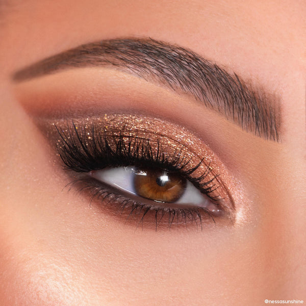 Shimmery bronze and copper glitter eyeshadow sweeps across a brown eye with long lashes and a defined brow, created using the Feelin Wild Shadow Palette Set, a ColourPop Shadow Palette, in a tight beauty close-up.