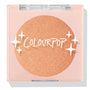 Boombox compact showcasing a closed ColourPop Pressed Powder Highlighter in shade Boombox, a warm peach‑gold shimmer pan set in a pale pink square case with a clear lid, white star accents, and the ColourPop logo.
